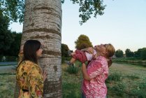 Side view of women showing tree to child at park — Stock Photo