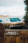 Крупним планом приватний знак на паркані і старовинний автомобіль, припаркований позаду — стокове фото