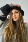 Stylisches junges Mädchen mit Mütze posiert und wegschaut — Stockfoto