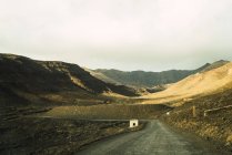 Paesaggio vista sulla valle in montagne sabbiose asciutte con strada solitaria in fuga . — Foto stock