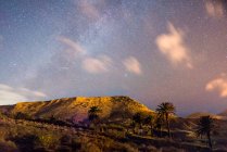 Panoramic view to hills and starry cloudy sky at night in countryside — Stock Photo