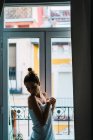 Ritratto di giovane donna avvolta in asciugamano e posa alla finestra a casa
. — Foto stock