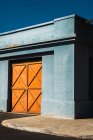 Vista exterior de puertas naranjas en pared azul - foto de stock
