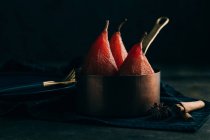 Still life of poached pears in copper sauce pot and cinnamon sticks — Stock Photo