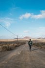 Вид спереду на туристичну людину, що біжить по дорозі в полі — стокове фото