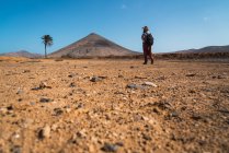 Vue arrière de l'homme avec sac à dos marchant dans le désert tropical — Photo de stock