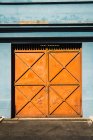 Exterior shot of building blue facade with metal orange gates in sunlight. — Stock Photo