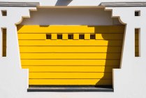 Зовнішній знімок білого декоративного фасаду з жовтим панно в яскравому сонячному світлі . — стокове фото