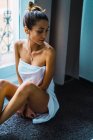 Retrato de mulher em toalha sentado no peitoril da janela — Fotografia de Stock