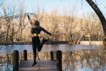 Ritratto di donna allegra che salta sul molo al parco — Foto stock