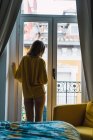 Rückansicht einer Frau, die auf Fenster im Schlafzimmer blickt — Stockfoto