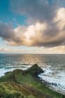 Vista idilliaca sulla verde roccia costiera al mare nelle giornate di sole — Foto stock