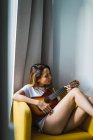 Молода жінка сидить і грає на гітарі — стокове фото