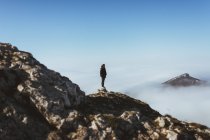 Man on rocky cliff in clouds — Stock Photo