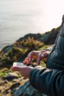 Земледелец с помощью смартфона на прибрежном холме — стоковое фото