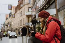 Side view of bearded man using smartphone in city — Stock Photo