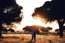 Pareja romántica abrazándose en medio del campo al atardecer en Madrid, España - foto de stock