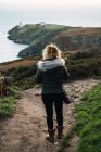 Вид сзади на женщину, идущую по берегу — стоковое фото