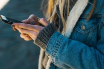 Ritaglia le mani femminili digitando sullo smartphone — Foto stock