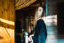 Sinnliche Blondine im Pullover lehnt an Tür und blickt in die Kamera — Stockfoto
