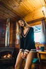 Young girl wearing sweater posing sensually inside of small cozy cottage. — Stock Photo