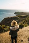 Rückansicht einer Frau, die auf Hügeln an der Küste steht — Stockfoto