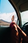 Crop piedi maschili sporgenti dal finestrino dell'auto sullo sfondo della valle di montagna — Foto stock