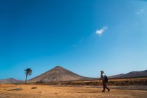 Вид сбоку человека с рюкзаком, идущего по пустыне — стоковое фото