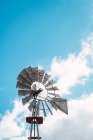 Vista de alto ângulo do velho moinho de vento de metal girando no fundo do céu azul . — Fotografia de Stock