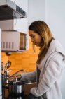 Vista laterale della giovane donna che cucina in cucina — Foto stock