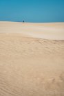 Distant view anonymous traveler in sandy dunes — Stock Photo