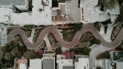 Dall'alto vista aerea alla strada a forma di serpente in città urbana . — Foto stock