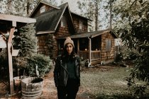 Pretty woman on background of wooden house in forest — Stock Photo