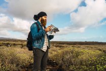 Seitenansicht eines Touristenmannes mit Rucksack und Landkarte in der Hand auf dem Land — Stockfoto