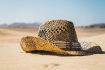 Закрыть вид на соломенную шляпу на песке — стоковое фото