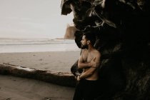 Без сорочки чоловік позує біля багажника на океанічному пляжі — стокове фото