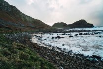 Stones and green hill at seashore — Stock Photo