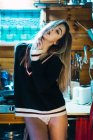 Provocative girl in sweater posing on kitchen counter — Stock Photo