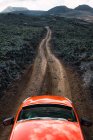 Червоний автомобіль їде по дорозі в сільських пагорбах — стокове фото