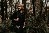 Touriste marchant dans la forêt d'automne et regardant de côté — Photo de stock
