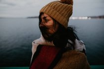 Vue latérale de la jeune femme posant dans le vent sur fond de paysage marin — Photo de stock