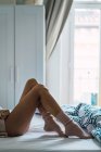 Обрізати жіночі ноги, лежачи і розслабляючись в ліжку вдома . — стокове фото