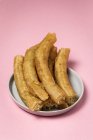 Delicious Spanish churros in plate on pink — Stock Photo