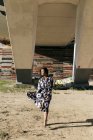 Donna in bel vestito camminare sotto il ponte e distogliere lo sguardo — Foto stock