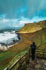 Vista traseira do turista em pé no miradouro e tirar fotos de colinas e mar — Fotografia de Stock