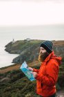 Seitenansicht eines bärtigen Mannes, der mit Landkarte an der Küste posiert — Stockfoto