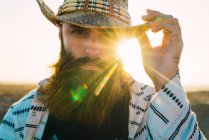 Porträt eines bärtigen Mannes, der mit Hut gegen Sonnenlicht posiert — Stockfoto