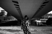 Portrait of woman in beautiful dress posing under bridge and looking down — Stock Photo