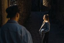 Visão traseira do homem olhando para a jovem mulher em pé sensualmente com os olhos fechados à luz solar . — Fotografia de Stock