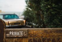 Cartello privato su recinzione in legno e auto d'epoca dorata a cespuglio . — Foto stock